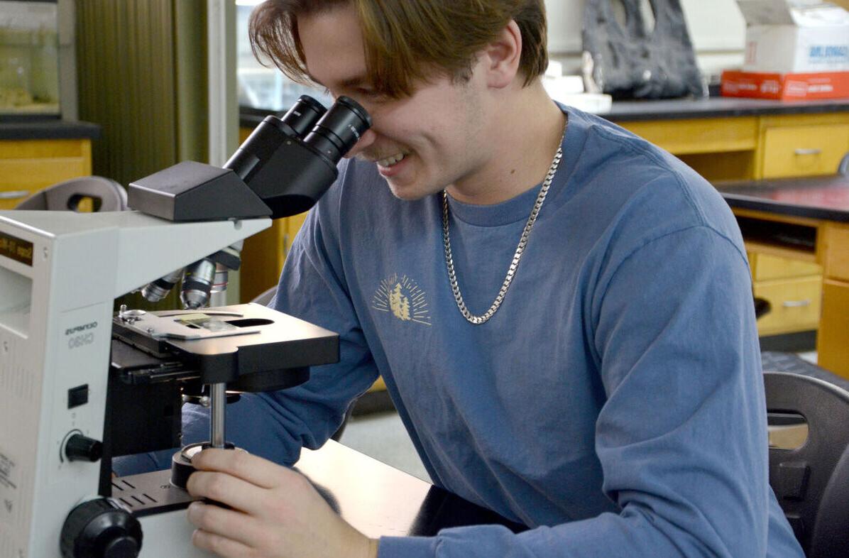 A male student looks through a microscope